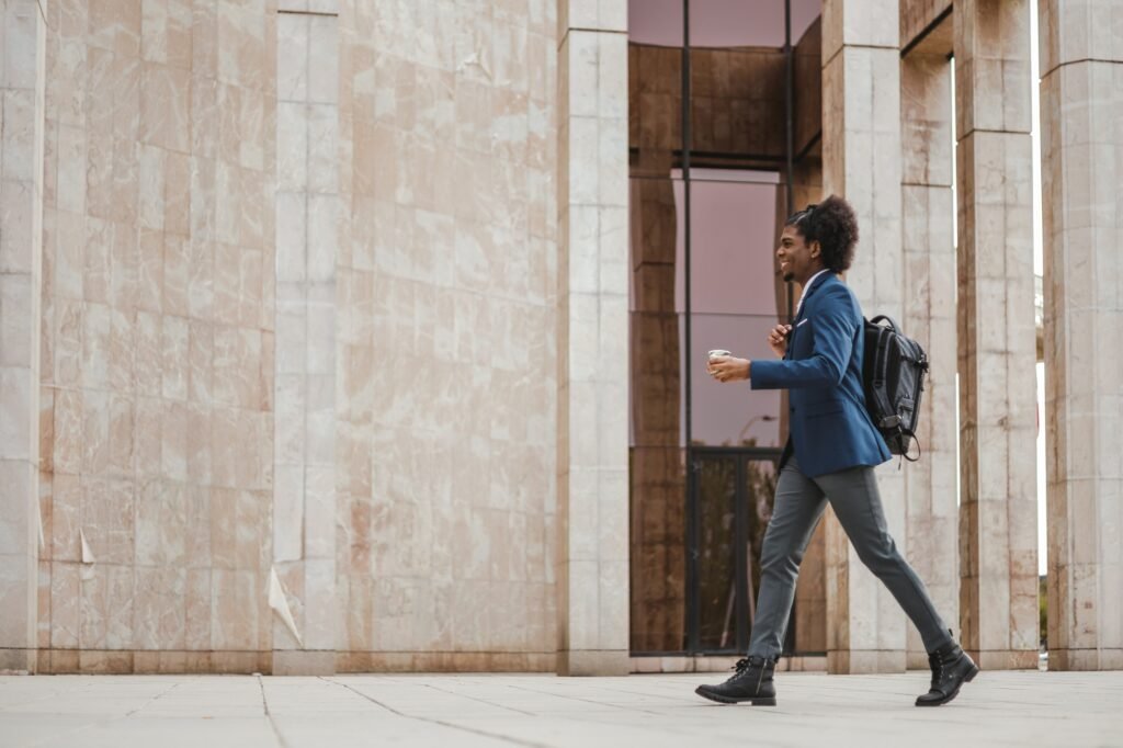 side view of african american businessman walking with backpack and coffee, copy space