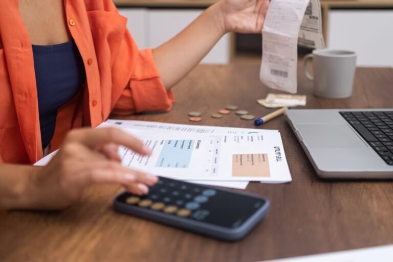 woman with a laptop, conducts household budget calculations on her smartphone calculator