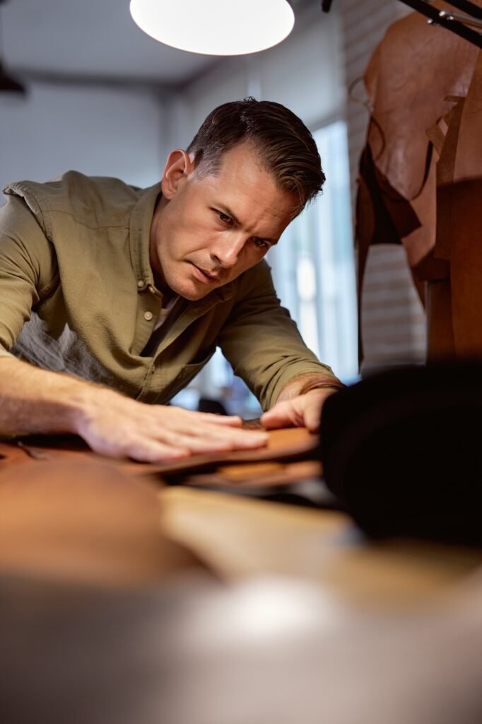 serious man concentrated on selecting leather for sewing bags