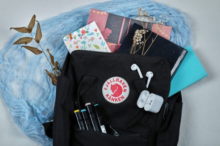 A backpack full of notebooks with headphones, flowers and pencils on the blue cloth