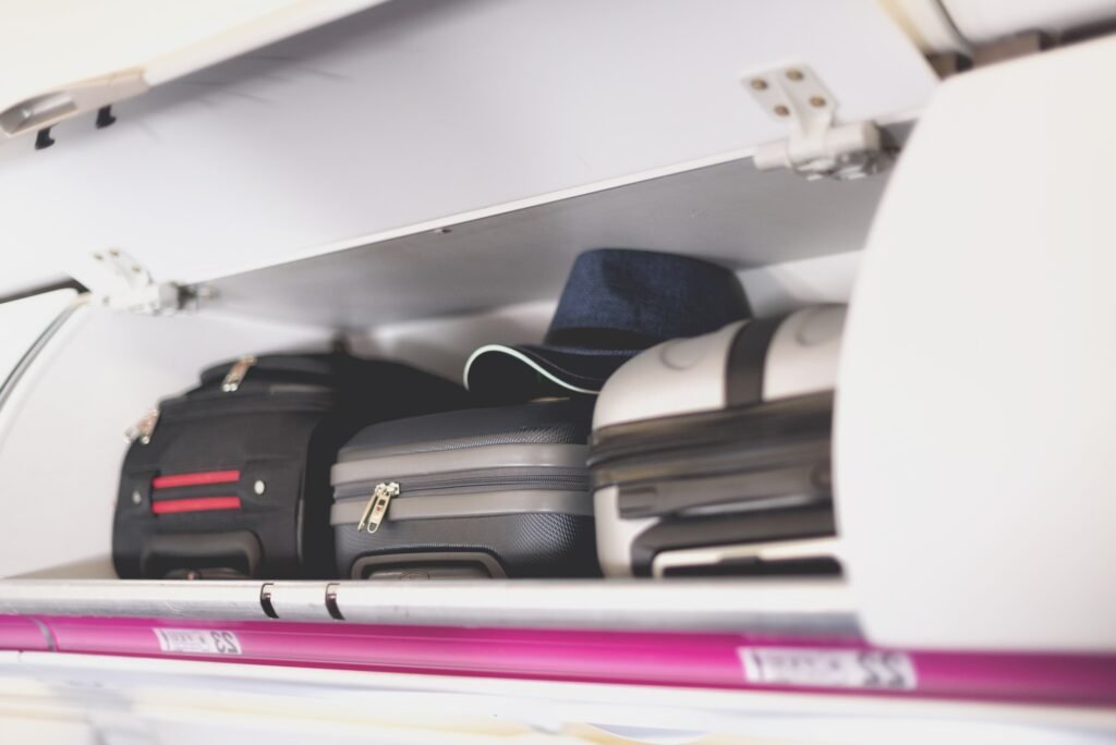 Hand-luggage compartment with suitcases in airplane. Carry-on luggage on top shelf of plane. Travel