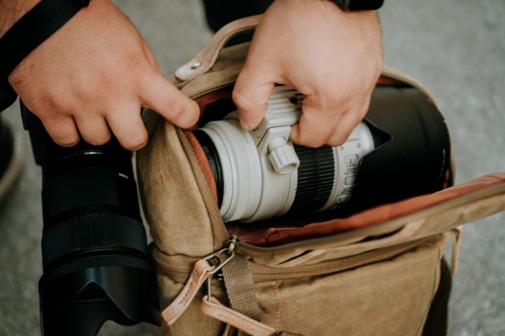 Photographer pulling out a white camera lens from a camera bag