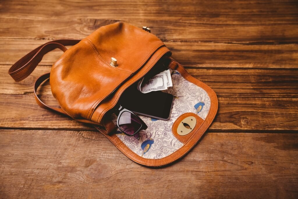 Sunglasses and wallet on the vintage bag on wooden table