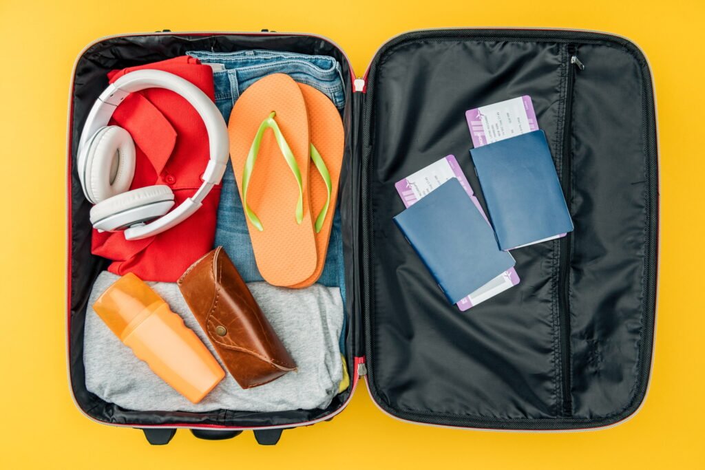top view of straw headphones, passports and air tickets in travel bag isolated on yellow