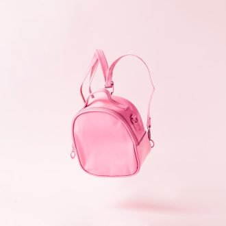Pastel pink school bag floating. Surreal modern still life. Back to school minimal concept.